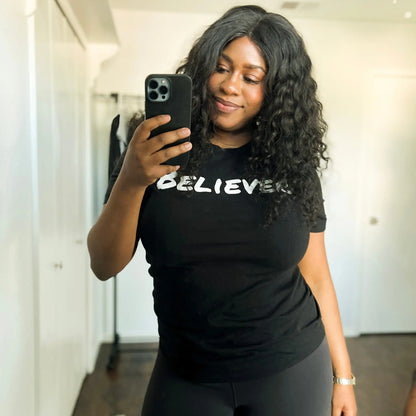 This T-shirt is all black with a crew neck style. The words Believer are pressed on the shirt in bold white letters. The T-Shirt is written across the chest, stretching from shoulder to shoulder. The T-shirt this comfortable and fitted. Size up for an oversized look. On a Neutral Colored background. The back reads John 3:16 on the tail of the T-Shirt.  