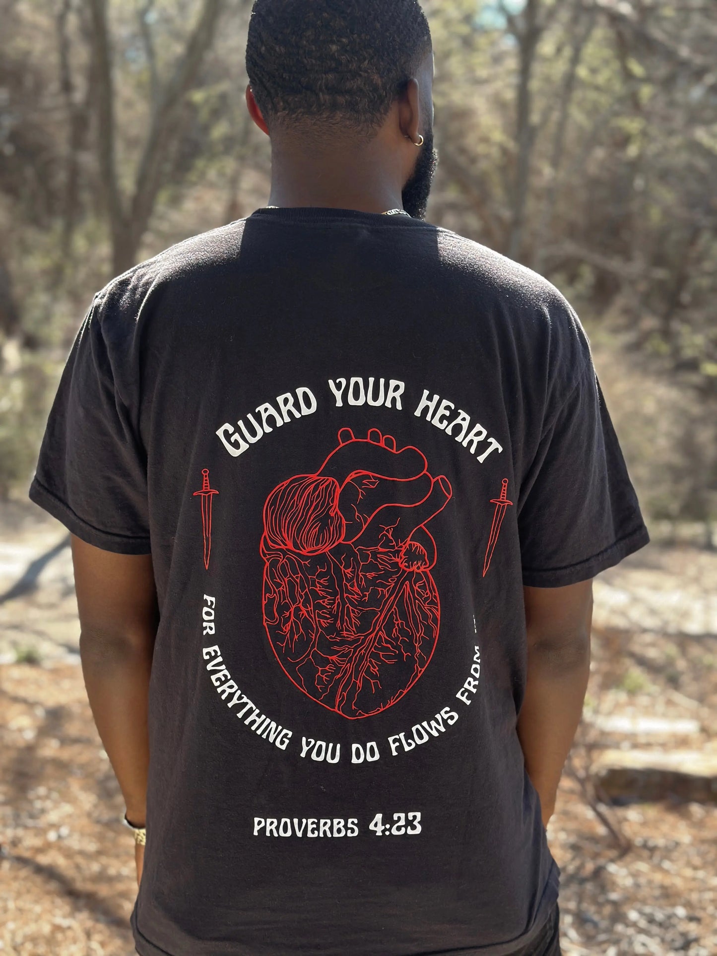 Guard your heart Tshirt. Red Heart T-shirt with swords on it and the verse Proverbs 4:23. Proverbs 4:23 Tshirt. Proverbs 4:23 Tshirt. Proverbs 4:23 black t-shirt from Crown of Favor. Crown of Favor guard your heart. For everything you do flows from it. . Christian clothing brand
